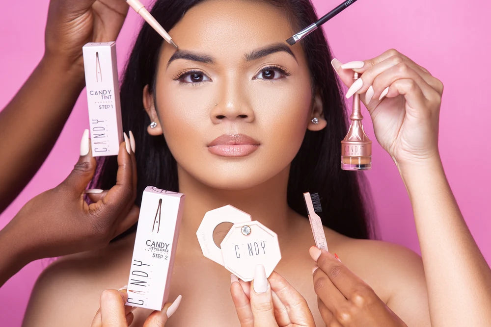 A Candy Brow Bar campaign photograph: a model framed by hands holding Candy products